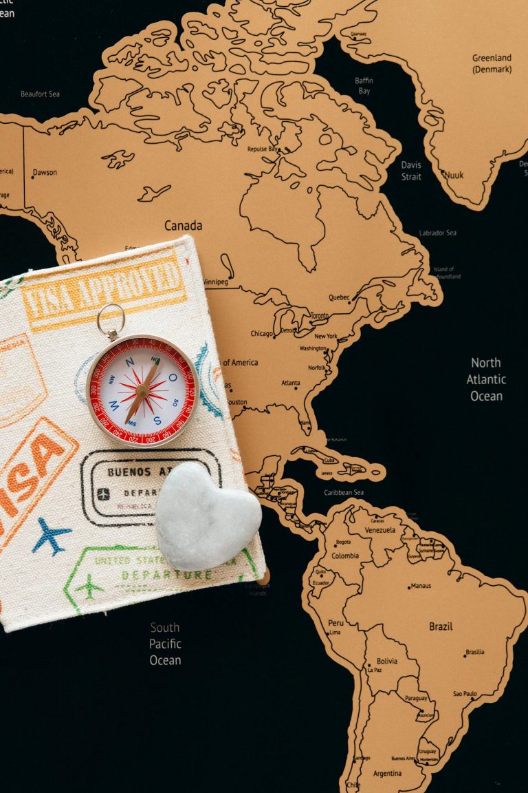 Flat lay photo of a map, passport, and compass, symbolizing travel and adventure.